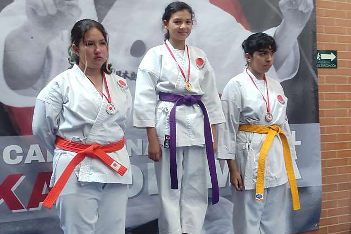 la estudiante Oriana Moreno en el podio de primer lugar, junto a otras concursantes en segundo y tercer lugar