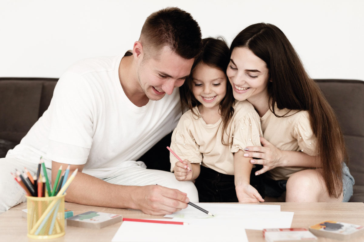 Familia conformada por el padre, la madre y una hija escribiendo su proyecto de vida