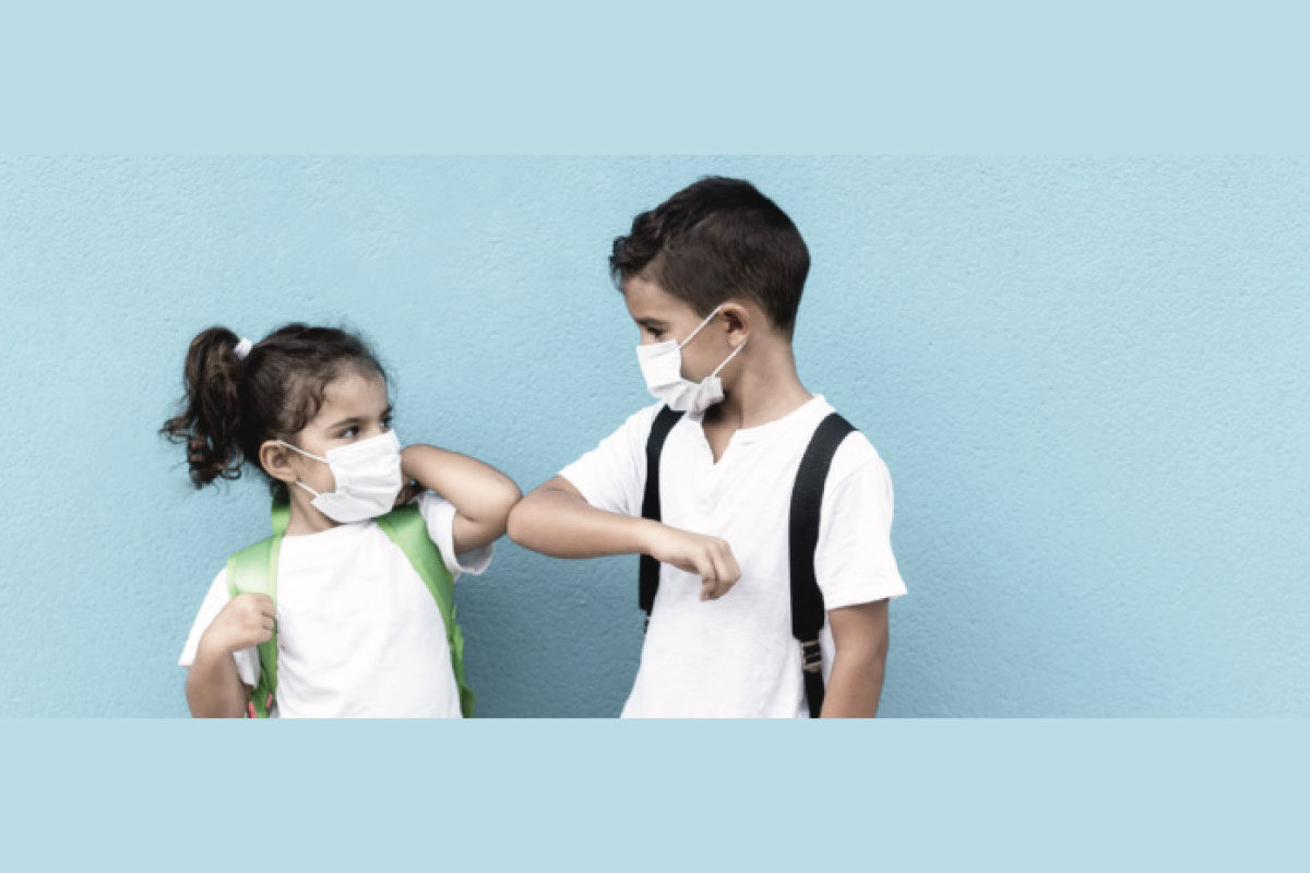 Fotografía de dos niños saludandose y usando tapabocas