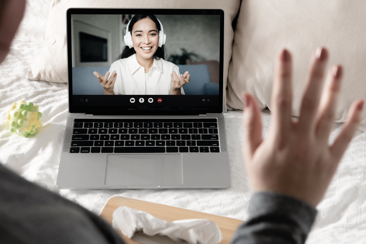 Conferencia virtual, una joven soludando desde un computador al que esta conectado