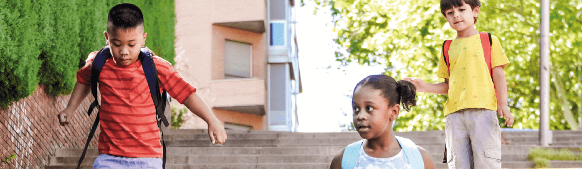 Tres niños estudiantes bajando escalas, en camino de inclusión